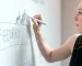 A women is writing on glass whiteboard